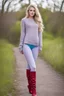 Placeholder: beautiful 18 year old girl with ash blonde hair and blue eyes with her curvy hair down, wearing a long-sleeved woollen top, and lilac long leggings, with long red boots full body shot