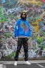 Placeholder: the coolest rapper ever with hoody and trendy clothes. graffiti wall in background are full of nft images and crypto currency symbols