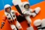Placeholder: Mike pence G.i. Joe toy doll Astronaut uniform inside a blister packaging hanging on a Wallrack in toystore, fluorescent orange, wide angle shot whole body, black moonboots, fullsize, bright green pricetag,