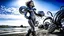 Placeholder: Wide-angle shot of a woman, standing to one side, with dark hair in a silver robotic catsuit, standing on a beach, flying mushrooms with octopus tentacles floating above her