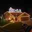 Placeholder: photograph taken by a gopro camera of a suburban house with an insanely detailed Chistmas light display lit up at night. Christmas lights on everything, Santa's sleigh and reindeer on roof all lit up with individual christmas lights,