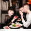 Placeholder: Russian guy young widow boyish boylike short man's haircut men's face boyish features in black girlish lacy cocktail dress as mother in restaurant