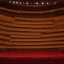 Placeholder: a single chair on stage under spotlight at a dark and empty symphony hall