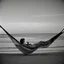 Placeholder: mujer sentada en una hamaca de madera en la playa, fotografía real, fotografía realizada con un cámara Fuji y objetivo de 35mm, fotografía en blanco y negro, tono años 60