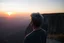 Placeholder: a large young man with grey hair views sunset from a cliff
