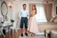 Placeholder: very beautiful lady with beautiful midi skirt and pretty top standing next to her boy freind in a luxury bedroom with high heels next to makeup desk looking to camera