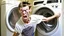 Placeholder: very skinny and lanky young man angry and can't push damaged washer and dryer