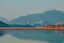 Placeholder: Sunny day, distant modern city, lake, lake reflections, people, mountains