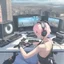 Placeholder: photorealistic femboy playing video games on en enormous gaming set up in a middle of a city