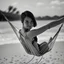 Placeholder: mujer sentada en una hamaca de madera en la playa, fotografía real, fotografía realizada con un cámara Fuji y objetivo de 35mm, fotografía en blanco y negro, tono años 60