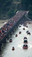Placeholder: Thousands of people crossing a bridge that caused the bridge to collapse in the water, many boats are rescuing people