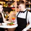 Placeholder: Russian guy young wife boyish boylike short man's haircut men's face boyish features in black girlish lacy cocktail dress as mother in restaurant