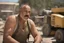 Placeholder: photography of a marocan ugly burly serious wet sweaty, beefy strong fat carpenter, shirtless, in overall, bulge, manly chest, big salt-and-pepper mustache 52 years old, short hair, sitting with open legs on a little chair , on a construction site in the middle of a road, under the August sun, angry eyes, , hyper-realistic, photorealistic , frontal view from the ground