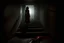 Placeholder: a broken, bloody, torn, beaten woman lies at the bottom of a dirty staircase. At the top of the stairs stands the silhouette of a massive man, behind him a small light leaks through an open door, dramatic, gloomy atmosphere, sad, weird, dark colors, cinematic, realistic picture