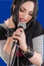 Placeholder: attractive female country music singer leaning forward while holding microphone in one hand, other hand brought up to side of neck, change clothing to plaid in natural tones, leather bracelets on wrists, long hair, mouth open singing, rings on fingers, eyes closed