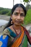 Placeholder: a beautiful 40 year old woman wearing a modern saree, standing near a tree, long face