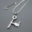 Placeholder: Clear polyester necklace with a chunky silver pendant in the shape of a key