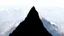 Placeholder: looking up at a single sharp narrow mountain, the peak obscured by clouds and fog.
