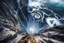 Placeholder: at the base of the rocky mountain peninsula, a great whirlpool waterfalls into deeper unknown depths