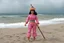 Placeholder: [1960’s stop-motion animation style on the beach the overcast sky in the background] a 70s advertisement video TV featuring A surprised Nomadic samurai woman, 24-years-old wearing a pink one-piece swimsuit , poised on hands and knees as a claymation character toy from a claymation horror movie in burning rainbow land, from hell, creepy Videos, eyeballs and trees everywhere , as old advertisement shot on video VHS