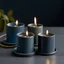 Placeholder: Three candle holders in different sizes and heights, with denim blue candles and burning wicks