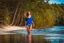 Placeholder: beautiful girl in blue short and orange top walking in water toward camera in trees next to wavy river with clear water and nice sands in floor.camera capture from her full body front