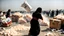 Placeholder: A Palestinian woman wearing a dress carrying very large bags of flour on her back, bending her back down in the destroyed Gaza City, and aid boxes descending from planes near the sea, with a large number of children looking up.