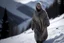Placeholder: Una mujer mayor con la cara borrosa y mirada lateral, vestida con un camisón, camina sobre la nieve en un paraje de alta montaña. Fotografía con cámara Leica y objetivo de 35 mm. Fotografía en Blanco y Negro
