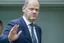 Placeholder: side view of Olaf Scholz walking, concerned expression, waving hand, pressed lips; in the style of VanGogh