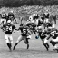 Placeholder: Boston Shamrocks Football team playing against the Toronto Rifles Football team,vintage footage, hyper-realistic, 1960s