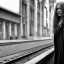 Placeholder: A young German woman with long hair and a black trench coat longingly waiting for her lover at a train station in Munich