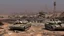 Placeholder: Israeli soldiers and tanks stand on a very large chessboard in the middle of a destroyed city