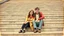 Placeholder: retro photo of a young couple in 70s style clothes sitting on the lower steps of the Danube stone embankment stairs in Budapest , the photo is old, stained and scratched in some places, one corner of the photo is missing, the girl's and the boy's faces are blurred and not clearly visible, behind them are many stairs