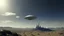 Placeholder: A small, long, sleek Spacecraft landing in a ruined alien city, clear sky, small white clouds