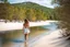 Placeholder: beautiful girl walking toward camera in trees next to wavy river with clear water and nice sands in floor.camera capture from her full body front