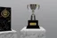 Placeholder: The trophy stands about 12 inches tall, and the base is a shiny, black marble pedestal with a silver plate on it, bearing the inscription "Champion's Triumph" in bold, elegant letters.