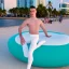 Placeholder: a gay ballet dancer dressed in white sitting on a beautiful coloured doughnut at ocean drive Miami