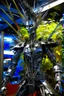 Placeholder: A humanoid being made entirely of sharpened metal blades and spikes stands before a mechanical tree. Photograph.
