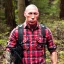 Placeholder: george st pierre bloody with a red plaid shirt a jean and a military backpack surviving in a forest