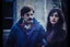 Placeholder: ayoung man and a beautiful woman standing next to each other, 1 9 7 0 s analog video, with mustache, assyrian, small glasses, cold scene, out of focus background, house on background, the woman has long dark hair, the photo shows a large, deiv calviz, before the final culling