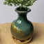 Placeholder: photo of a small cracked ceramic vase repaired with gold, kintsugi, lush greenery, natural setting, beautiful landscape photography, beautiful, vines and leaves, rosebuds, delicate, cinematic, high detail, beautiful composition, delicate arrangement, aesthetic, soft lighting, award winning photography, tender