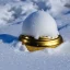 Placeholder: exquisite tiny gold bell half buried in snow, gentle snowy scene, soft lighting, snowdrift