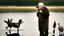 Placeholder: old man talks on phone while chasing ducks away, looking very confused