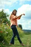 Placeholder: country side ,wild flowers, blosom pretty sky and cloudes a beautiful young lady wearing pants and blouse dancing gracefully in garden look at camera