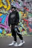 Placeholder: the coolest rapper ever with hoody and trendy clothes. graffiti wall in background are full of nft images and crypto currency symbols