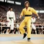 Placeholder: chuck norris in his iconic karate outfit in the arena, in front of Bruce Lee in yellow