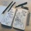 Placeholder: A bulletjournal with drawings and writing on a table with drawing tools