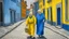Placeholder: Oil painting of a street scene with buildings in yellow, blue, and white, with a woman and child walking on the cobblestone street. The woman, possibly white, around 70 years old, has gray hair and is wearing a gray shawl. The child, around 5 years old, has red hair and is wearing a white coat. The buildings are simple in design, with small windows and doors. The sky is overcast, and the overall tone of the painting is muted. The brushstrokes are visible, and the colors are applied in a thick, i