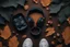 Placeholder: An overhead view of some wireless headphones lying on a floor full of dry leaves. Near the headphones, feet wearing Snickers sneakers approach.