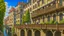 Placeholder: medieval buildings with balconies overhanging a river, blue sky and people, photorealism, trees, foliage, piers, intricate detail, ultra-sharp image, sharp focus